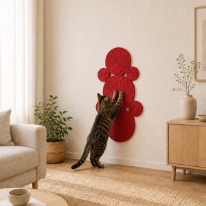 K&ouml;nnte beinhalten: Ein an der Wand montierter Kratzbaum f&uuml;r Katzen, bestehend aus mehreren miteinander verbundenen, roten kreisf&ouml;rmigen Scheiben, die mit dickem Seil umwickelt sind. Die Struktur verf&uuml;gt &uuml;ber einen gro&szlig;en Mittelkreis und kleinere Kreise.