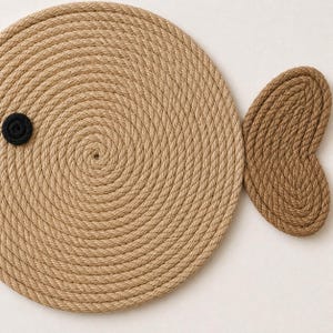 Pu&ograve; includere: Un sottopentola decorativo a forma di pesce realizzato con corda naturale avvolta. Il corpo del pesce &egrave; una forma grande e circolare con un piccolo occhio circolare nero. La coda &egrave; un pezzo pi&ugrave; piccolo a forma di cuore.