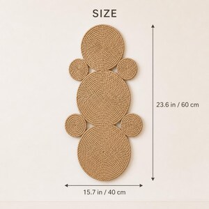 K&ouml;nnte beinhalten: Ein Wandbehang aus sieben beigefarbenen, spiralf&ouml;rmig gewickelten Seilkreisen in vertikaler Anordnung. Der Text SIZE steht oben. Die Ma&szlig;e sind mit 60 cm H&ouml;he und 40 cm Breite angegeben und zeigen die Gesamtgr&ouml;&szlig;e des Seilkunstobjekts.