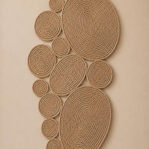 May include: A wall hanging composed of multiple circular and oval shapes made from coiled tan rope. The arrangement features varying sizes of discs and ovals tightly wound in a spiral pattern, creating a textured, layered composition of natural fiber.