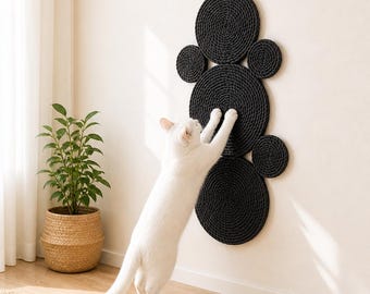 Könnte beinhalten: Ein wandmontierter Kratzbaum für Katzen, bestehend aus sechs miteinander verbundenen schwarzen, kreisförmigen Scheiben aus gedrehtem Seil. Die Scheiben sind in einer vertikalen Gruppe unterschiedlicher Größe angeordnet.