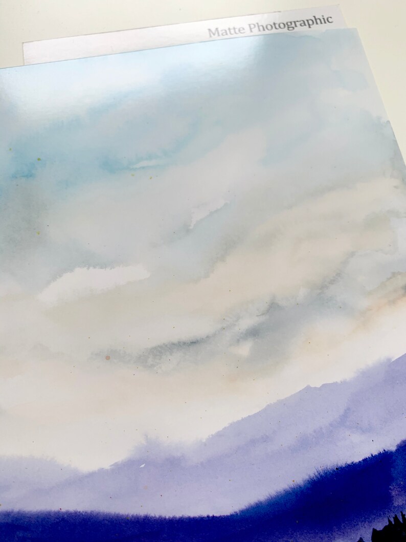 May include: A watercolor painting of a sky with clouds in shades of blue and gray, transitioning to a purple and blue mountain range at the bottom.