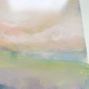 May include: Abstract painting with a soft, dreamy landscape. The painting features a light pink and yellow sky with white clouds, a green field, and a purple and blue foreground. The painting has a textured surface and a matte finish.
