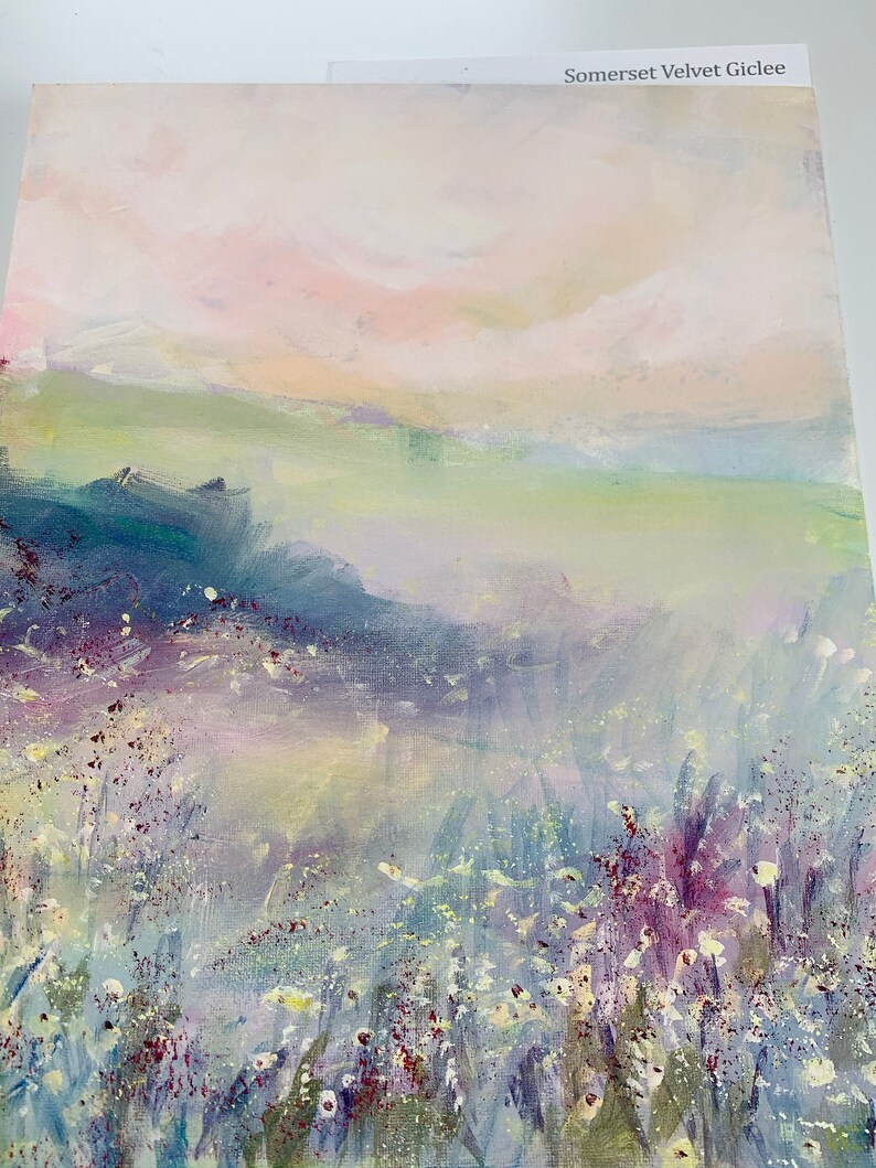 May include: A painting of a landscape with a soft, hazy sky in shades of pink and white. The foreground features a field of white flowers with purple and green accents. The painting has a dreamy, ethereal feel.