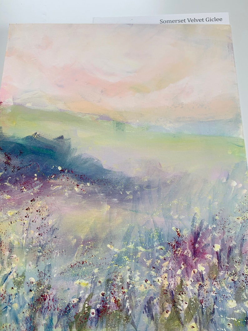 May include: An abstract landscape painting with a soft color palette of pink, green, and blue. The artwork features a field of wildflowers in the foreground and a hazy sky. The text "Somerset Velvet Giclee" is visible.