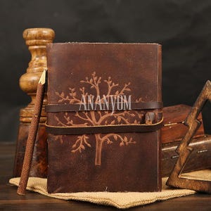 May include: A white ceramic mug with a black handle and the text "But First, Coffee" in a handwritten style. The mug is on a white surface. The mug is approximately 4 inches tall.