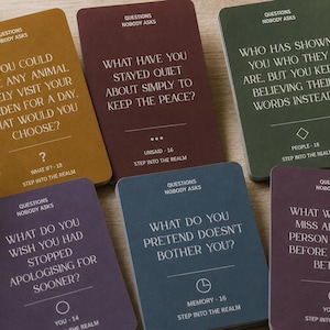 Puede incluir: Un conjunto de seis tarjetas rectangulares del juego Questions Nobody Asks, con colores variados que incluyen mostaza, granate, verde bosque, morado y azul pizarra. Cada tarjeta muestra una pregunta reflexiva en fuente serif blanca.