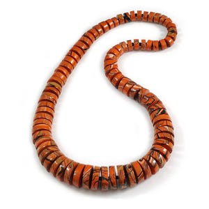May include: A necklace with orange and brown marbled beads. The disc-shaped beads are strung together, creating a curved design. The necklace has a warm, earthy colour, suitable for various outfits.
