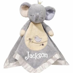 May include: A gray plush elephant security blanket with a cream-colored center featuring a bird design. The blanket has a satin trim and the name "Jackson" embroidered in white.