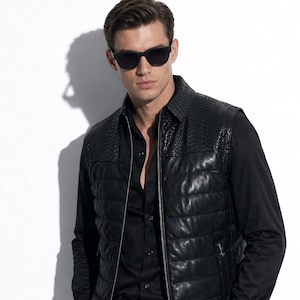 Peut inclure: Un gilet en cuir noir avec un design matelassé et un col texturé reptile. Le gilet a une fermeture éclair et est porté sur une chemise noire boutonnée. La personne porte des lunettes de soleil noires.