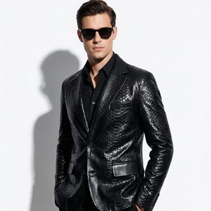 May include: A black leather blazer with a textured pattern, paired with a black button-down shirt and black pants. The blazer has a notched lapel and a single-button closure. The person is wearing black sunglasses.