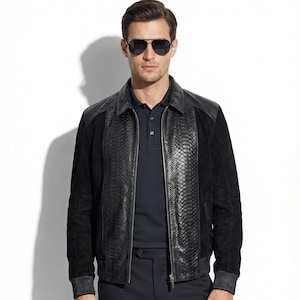 Peut inclure: Veste en cuir noir avec un panneau avant texturé en peau de serpent et des panneaux latéraux en daim. La veste a une fermeture éclair, un col et des poignets côtelés. La personne porte des lunettes de soleil et un polo bleu foncé.