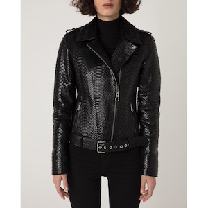 Könnte beinhalten: Schwarze Lederjacke mit Schlangenleder-Textur. Die Jacke hat einen Reverskragen, einen asymmetrischen Reißverschluss und einen Gürtel in der Taille. Sie hat lange Ärmel und eine taillierte Silhouette.