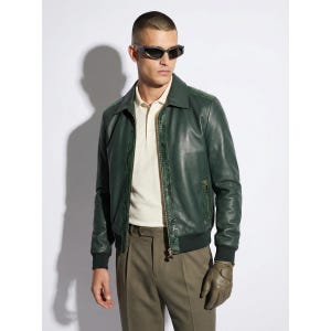 May include: A dark green leather jacket with a collared neckline and a zipper closure. The jacket has a ribbed hem and cuffs. The person in the image is wearing a light-colored polo shirt and olive-green pants. The person is also wearing dark sunglasses and gloves.