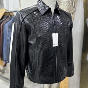 Peut inclure: Une tasse en c&eacute;ramique blanche avec une anse noire et le texte "But First, Coffee" en noir, en gras. La tasse est pos&eacute;e sur une surface blanche. La tasse mesure environ 10 cm de haut.