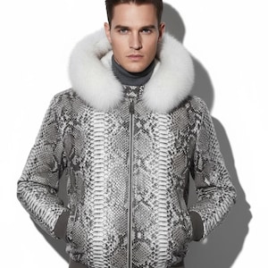 Könnte beinhalten: Grau-weißes Jacke mit Schlangenmuster und Kapuze mit weißem Pelzbesatz. Die Jacke hat einen Reißverschluss und einen grauen Rippsaum und Bündchen. Die Person im Bild trägt einen grauen Rollkragenpullover.