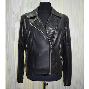 Op de afbeelding: Zwarte leren jas met een kraag, schouders en mouwen met slangenleertextuur. De jas heeft een diagonale ritssluiting en meerdere zilveren ritsen. De jas wordt gepresenteerd op een zwarte etalagepop.