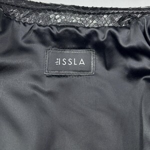 Peut inclure: Une tasse en c&eacute;ramique blanche avec une anse noire et le texte "But First, Coffee" en noir gras. La tasse est pos&eacute;e sur une surface blanche. La tasse mesure environ 10 cm de haut.