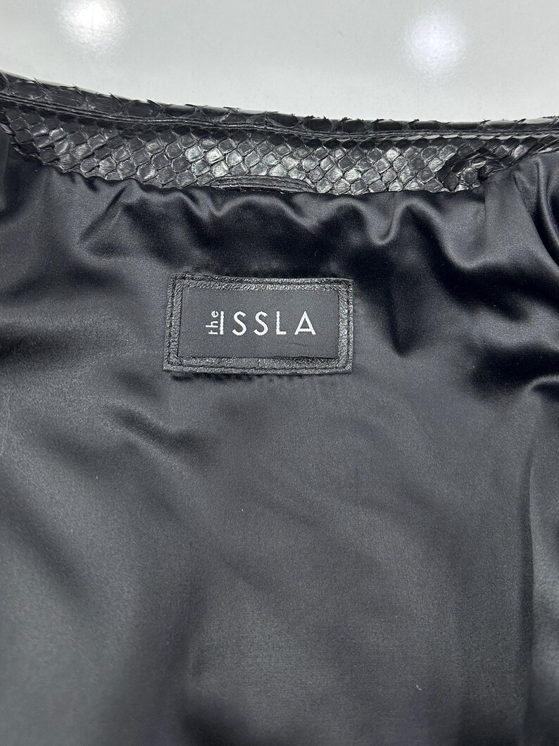 Peut inclure: Une tasse en c&eacute;ramique blanche avec une anse noire et le texte "But First, Coffee" en noir gras. La tasse est pos&eacute;e sur une surface blanche. La tasse mesure environ 10 cm de haut.