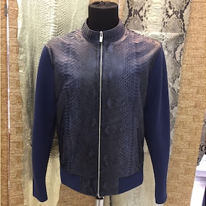 May include: A navy blue leather jacket with a snakeskin pattern on the front and a zipper closure. The sleeves are a solid navy blue. The jacket is displayed on a black mannequin.