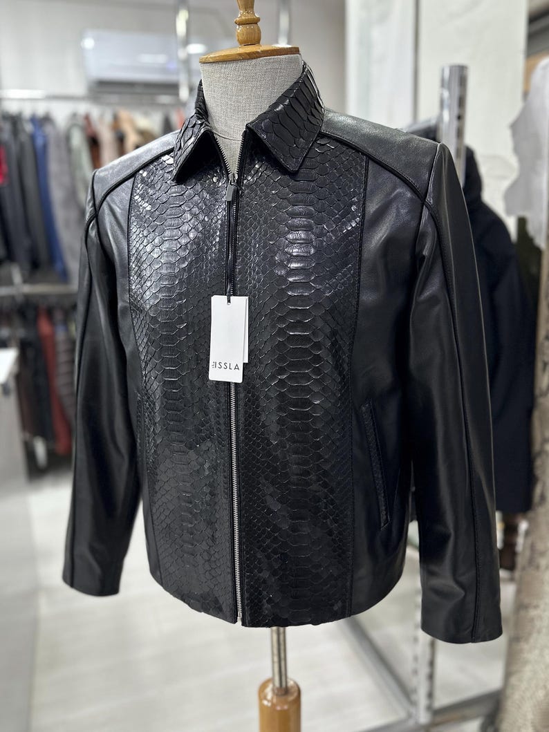 Peut inclure: Une tasse en c&eacute;ramique blanche avec une anse noire et le texte "But First, Coffee" en noir, dans une police manuscrite. La tasse est pos&eacute;e sur une surface blanche.