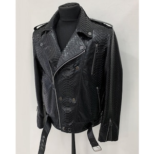 Op de afbeelding: Zwarte leren bikerjack met een slangenleertextuur. De jas heeft een asymmetrische ritssluiting, reverskragen en meerdere zakken. Het heeft een riem in de taille en ritsen op de mouwen. De jas wordt gepresenteerd op een zwarte mannequin.