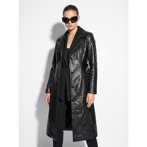 Könnte beinhalten: Ein langer, schwarzer Ledermantel mit Schlangenmuster. Der Mantel hat einen Reverskragen, einen Gürtel und lange Ärmel. Die Person auf dem Bild trägt eine schwarze Sonnenbrille und schwarze Kleidung.