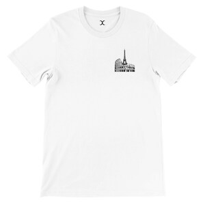 May include: White t-shirt featuring a black and white graphic of the Eiffel Tower and the Colosseum. The shirt has a crew neck and short sleeves. The graphic is located on the left chest area.