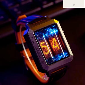 Puede incluir: Un reloj de pulsera futurista con una esfera rectangular que muestra los números "54" en naranja. El reloj tiene una caja plateada, una correa de cuero negro y una correa azul y naranja. El texto "NEONWORKS IN-16" es visible.