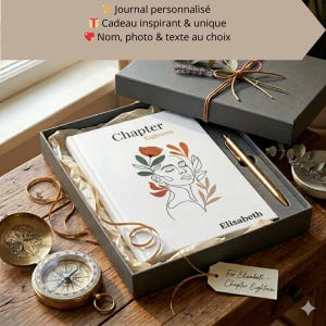 Peut inclure: Un journal personnalisé dans un coffret cadeau gris. La couverture blanche du journal présente un dessin au trait d'un visage féminin avec des accents floraux et le texte "Chapter Eighteen". Un stylo doré est inclus.