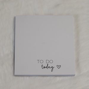 May include: A square white notepad with the text TO DO today printed in black ink near the bottom centre, accompanied by a small black heart icon. The notepad features a clean, minimalist design with ample blank space for writing tasks.
