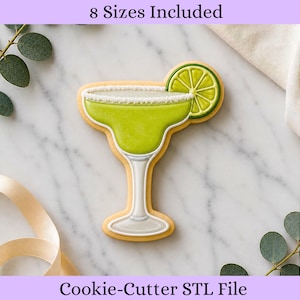 May include: A margarita cookie cutter in the shape of a cocktail glass with a lime wedge. The cookie has a green filling, a white sugar rim, and a white stem. The text "8 Sizes Included" and "Cookie-Cutter STL File" are visible.