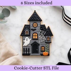 Peut inclure: Un biscuit en forme de maison hantée avec des murs gris, un toit noir à écailles et des fenêtres jaunes. Il présente un fantôme blanc, une toile d'araignée blanche, une chauve-souris noire et une citrouille orange. Texte 8 Sizes included et Cookie-Cutter STL File.
