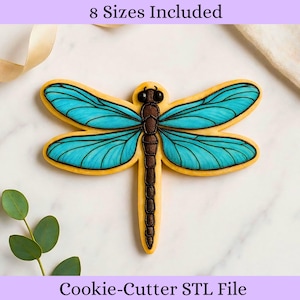 May include: A dragonfly-shaped cookie cutter with a yellow outline, teal wings, and a brown body. The image includes the text "8 Sizes Included" and "Cookie-Cutter STL File".