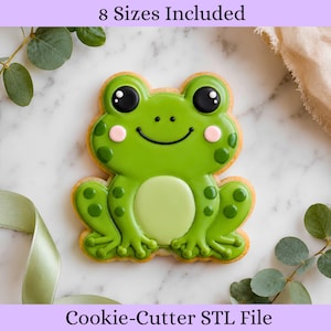 Può includere: Un biscotto a forma di rana con glassa verde, occhi scuri, guance rosa e macchie. Il testo 8 Sizes Included e Cookie-Cutter STL File è visibile. Il biscotto presenta una pancia verde chiaro e zampe palmate dettagliate come design digitale.