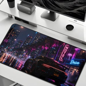 May include: A rectangular desk mat featuring a nighttime city street scene with a black Porsche 911 Turbo S parked in the foreground. The graphic includes neon pink and blue motel signage, palm trees, and wet pavement reflecting city lights.
