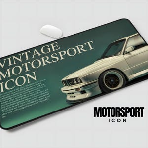 May include: A rectangular mousepad featuring a vintage white sports car with black wheels. The mousepad has the words "VINTAGE MOTORSPORT ICON" in white and "MOTORSPORT ICON" in black. The background is a gradient of teal and green.