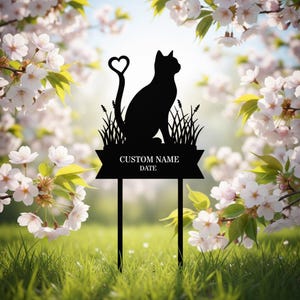 Könnte beinhalten: Schwarzer Metall-Katzen-Silhouette-Gartenstecker mit herzförmigem Schwanz. Die Katze sitzt auf einem Grasbüschel, darunter ein Banner mit der Aufschrift "CUSTOM NAME DATE". Der Stecker befindet sich in einem Garten mit weißen Blumen.