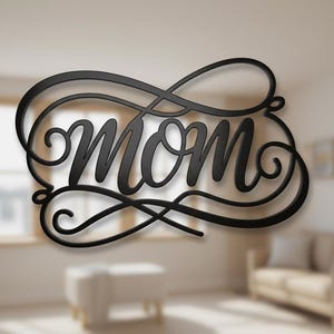 Könnte beinhalten: Schwarze Metall-Wandkunst mit dem Wort "MOM" in einer Schreibschrift, umrahmt von dekorativen Schnörkeln. Das Wort ist der Mittelpunkt und soll ein dekoratives Stück für ein Zuhause sein. Die Kunst ist an einer Wand montiert, mit verschwommenem Hintergrund.