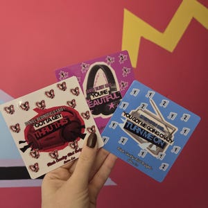 May include: Three square stickers featuring musical themes. One white sticker shows a red boombox with text "Gotta Get Thru This". A purple sticker displays black headphones with "You're Beautiful". A blue sticker shows a radio with "Turn Me On".