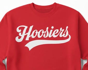 May include: A red crewneck sweatshirt with the word "Hoosiers" in white script across the chest. The word has a curved underline. The sweatshirt has long sleeves and a round neckline.