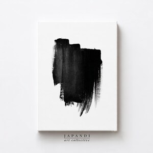 May include: Modern abstract art print. A large black brushstroke dominates the white canvas. The artwork has a contemporary feel, with the text "JAPANDI art collective" at the bottom. The black paint has a textured finish.