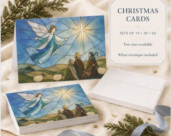 May include: Christmas cards featuring a stained-glass style illustration of an angel appearing to shepherds under a bright star. The cards are displayed with a stack of white envelopes and text that reads CHRISTMAS CARDS SETS OF 10 30 50.