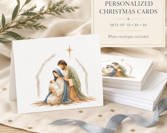May include: A set of white folded Christmas cards featuring a watercolour illustration of the Nativity scene with Mary, Joseph, and the infant Jesus under a gold star. A rectangular sign reads PERSONALIZED CHRISTMAS CARDS, SETS OF 10, 30, 50.