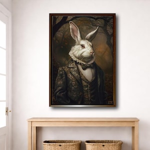 Könnte beinhalten: Ein gerahmter Kunstdruck, der einen weißen Hasen mit roten Augen zeigt, der eine dunkle, reich verzierte Weste, einen weißen Rüschenkragen und eine Fliege trägt. Der Hase ist vor einem dunklen, stimmungsvollen Waldhintergrund in Braun- und Goldtönen.