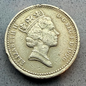 Puede incluir: Una moneda plateada que presenta un perfil de una cabeza coronada, con la inscripción "ELIZABETH II" y "D.G.REG.F.D.1996" alrededor del borde. La moneda tiene un diseño detallado y una apariencia ligeramente desgastada.