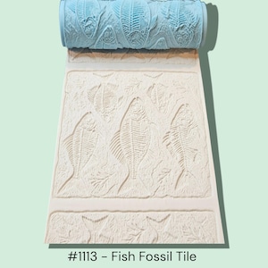 May include: A light blue patterned roller above a textured off-white surface with a fish fossil design. The design includes fish skeletons and leaf-like patterns. The text "#1113 - Fish Fossil Tile" is at the bottom.