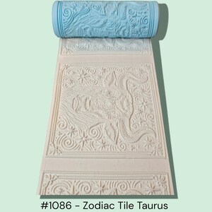 May include: A light blue patterned roller sits atop a beige tile with a detailed Taurus zodiac design. The tile features a border, stars, and scrollwork. The text "#1086 - Zodiac Tile Taurus" is visible at the bottom.
