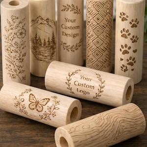 May include: A collection of wooden candle holders with various engraved designs. Some holders feature floral patterns, mountain scenes, geometric shapes, paw prints, and the text "Your Custom Design" and "Your Custom Logo".