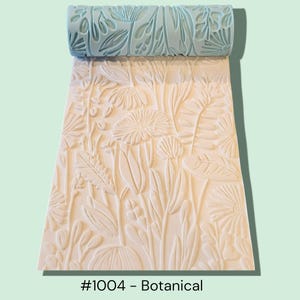 May include: A light blue botanical pattern roller and a cream-coloured surface with a floral design. The roller is embossed with a repeating pattern of leaves and flowers. The surface is stamped with the same botanical design. The text "#1004 - Botanical" is at the bottom.